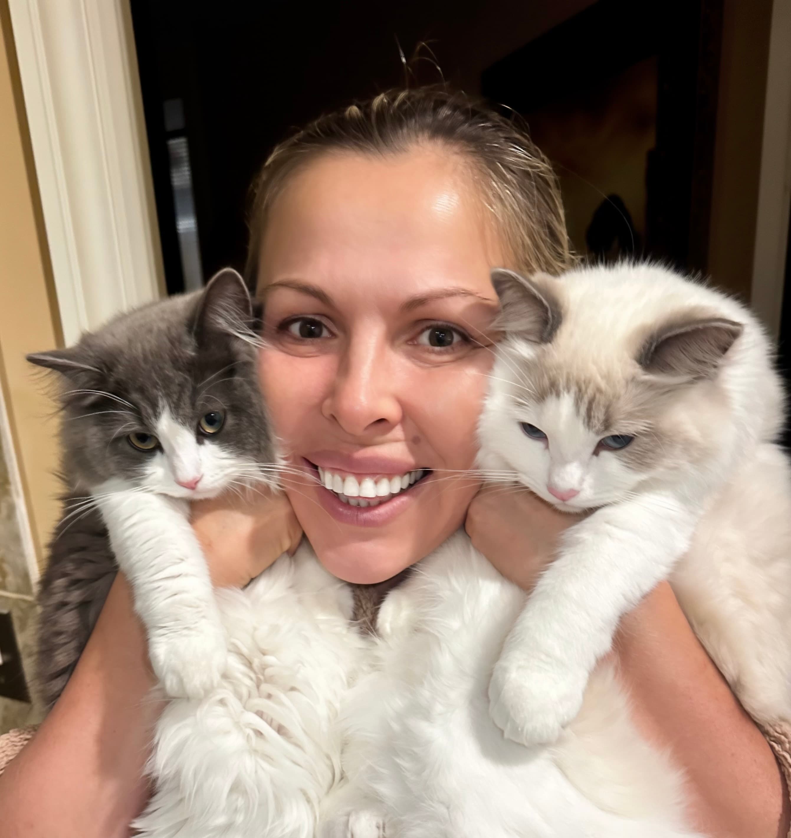 A happy breeder holding two of her kittens